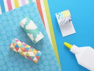 Tubes de papier toilette enveloppés dans du papier d'emballage coloré à motifs, découpés et fixés avec de la colle.