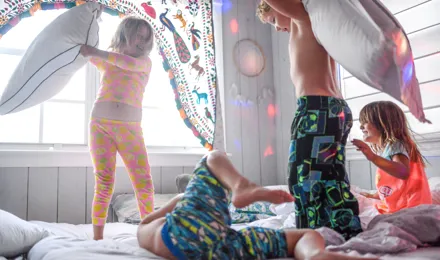 4 enfants faisant une bataille de polochons lors d'une soirée pyjama