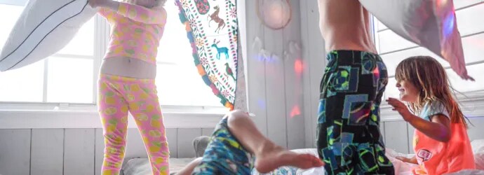 4 enfants faisant une bataille de polochons lors d'une soirée pyjama