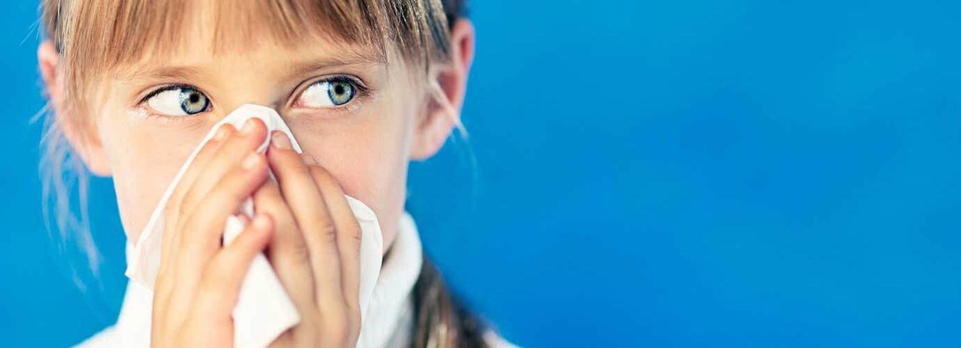 Flunssainen tyttö pitelee paperinenäliinaa nenänsä edessä