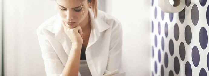 Une femme qui lit le journal aux toilettes