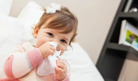 Une petite fille essuie son nez avec un mouchoir