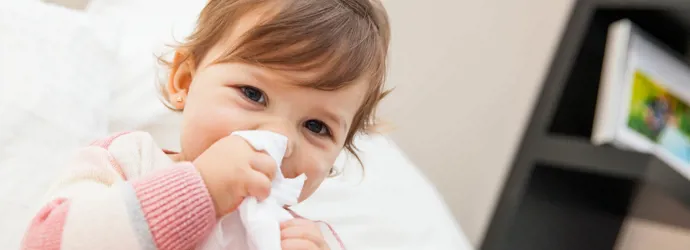 Une petite fille essuie son nez avec un mouchoir