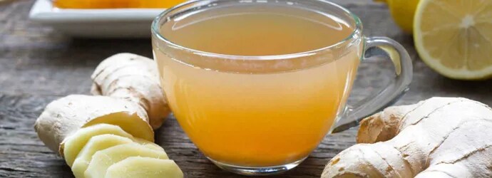 Du gingembre entier et haché, du miel, du citron et un verre de mélange sur une table en bois