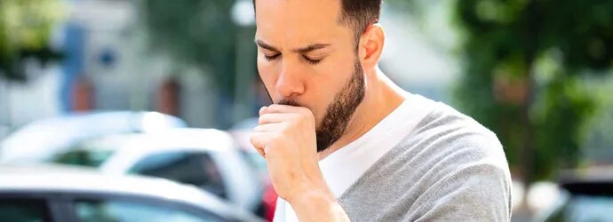 Un homme tousse, il est entouré de voitures