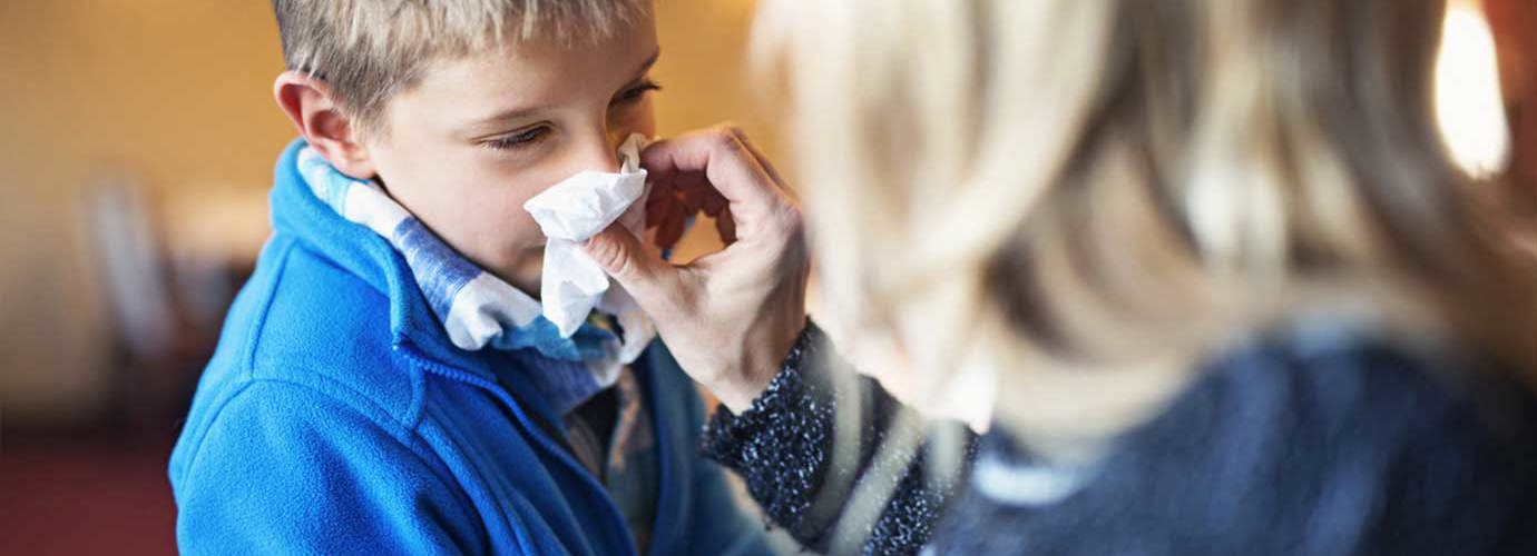 Une mère mouche le nez de son enfant et peut se demander ce qu'il faut faire pour éviter la propagation du rhume