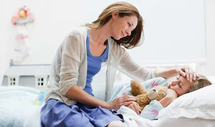 Une mère s'occupe de sa fille dans son lit avec un rhume