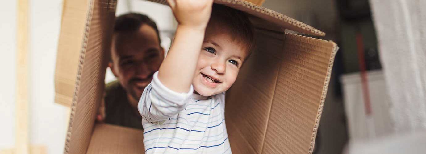 Un petit garçon tient une boîte en carton pendant un déménagement avec sa famille