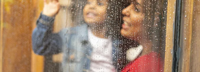 Mère et enfant regardant la pluie à travers la fenêtre