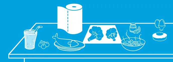 Nuori nainen käyttää kannettavaa tietokonetta ja syö terveellistä salaattia pöydän ääressä