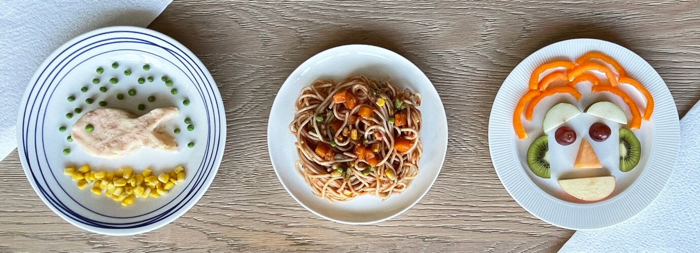Taapero nauttii ruuastaan ja hymyilee keittiön pöydän ääressä