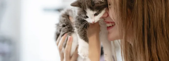 Jeune fille tenant un chaton près de son visage en souriant